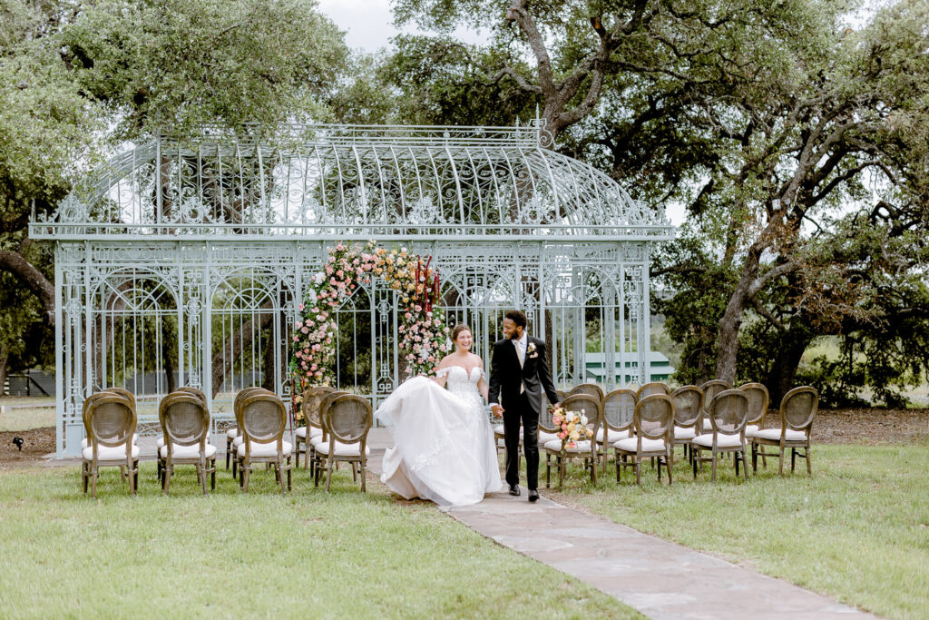 bride and room walking in front of greenhouse venue at Ma Maison