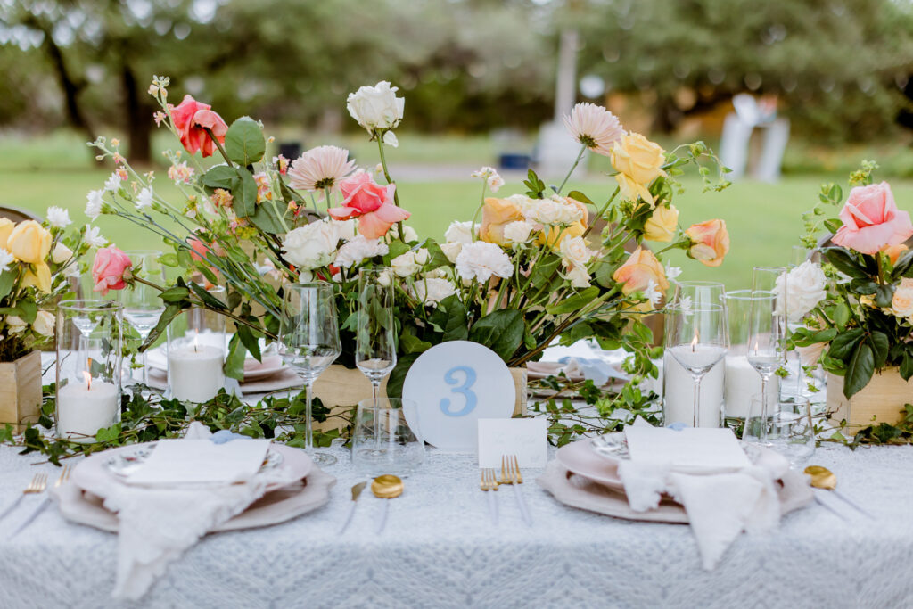 floral arrangements on a wedding reception table at Ma Maison wedding venue in Dripping Springs, Texas, with a number sign and cutlery