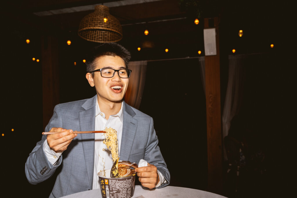 Asian man eating ramen at wedding reception at Ma Maison wedding venue