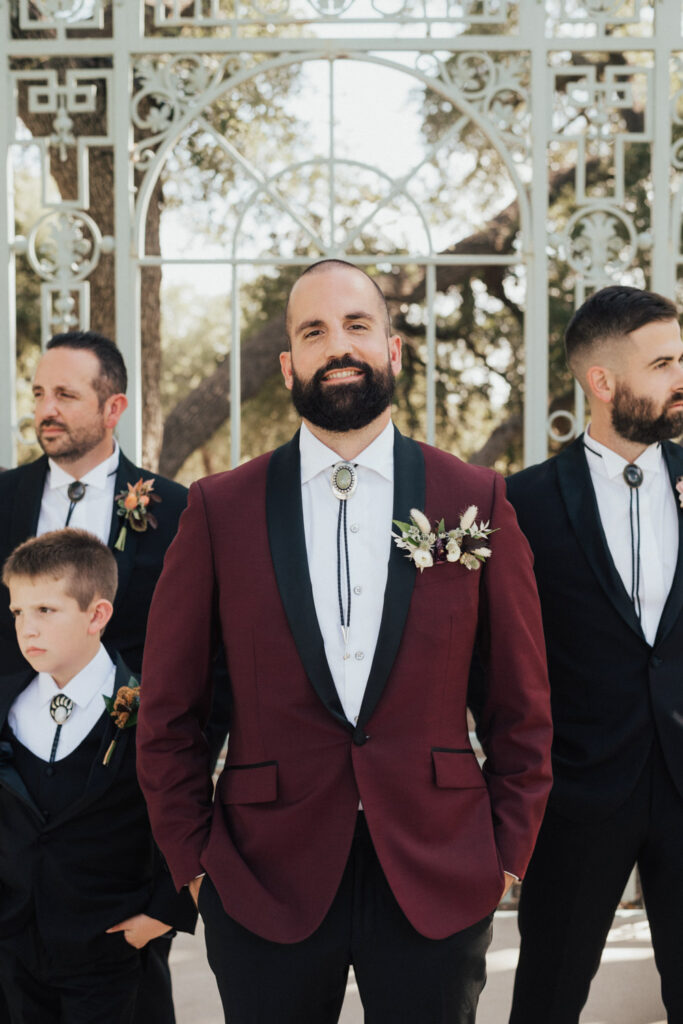 Groom in burgundy suit with groomsmen