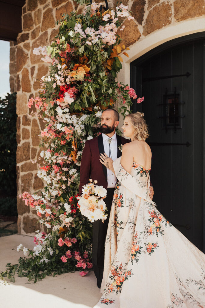 Bride and groom posing by floral arch at non barn wedding venue in Austin