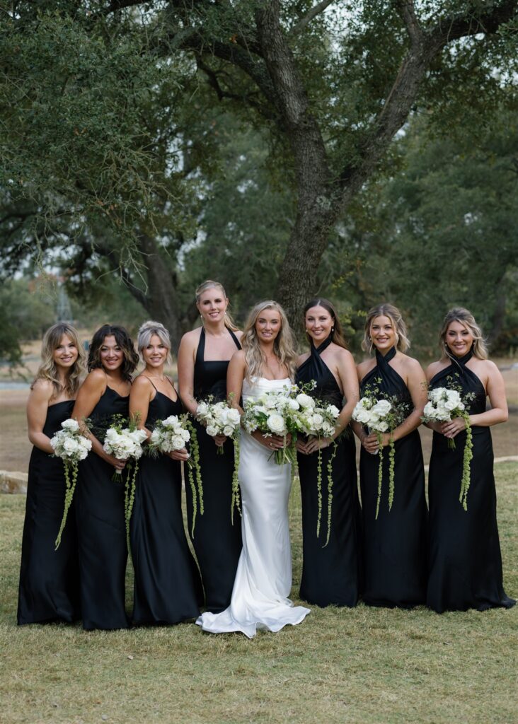 1. Bride with bridesmaids in black dresses holding white and green bouquets.