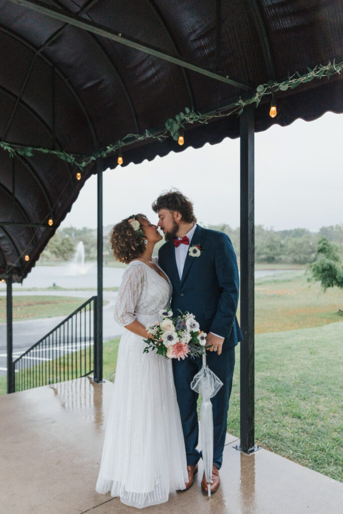 Bride and groom kiss under canopy of Ma Maison