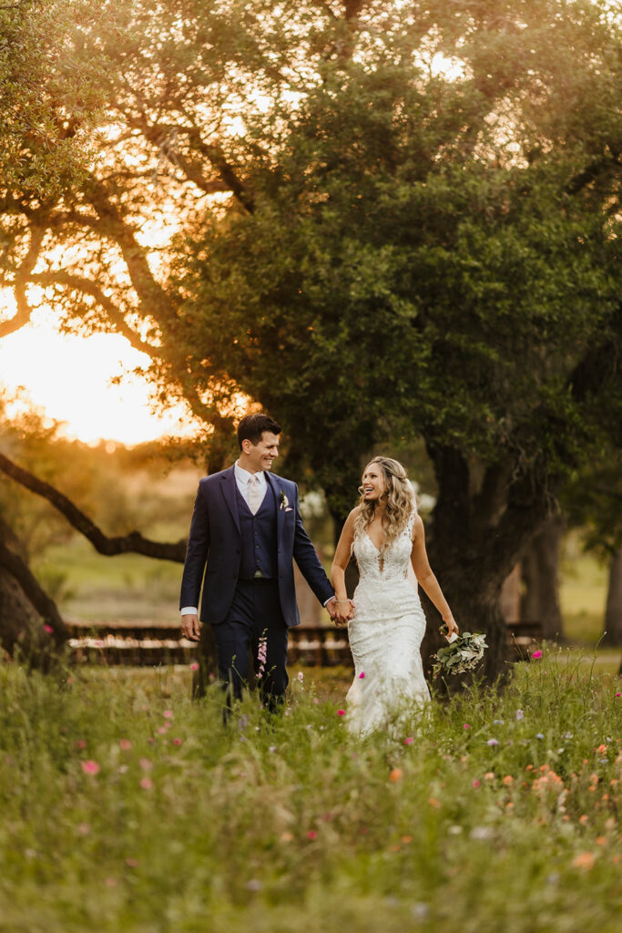 The couple walks hand in hand through a wildflower field