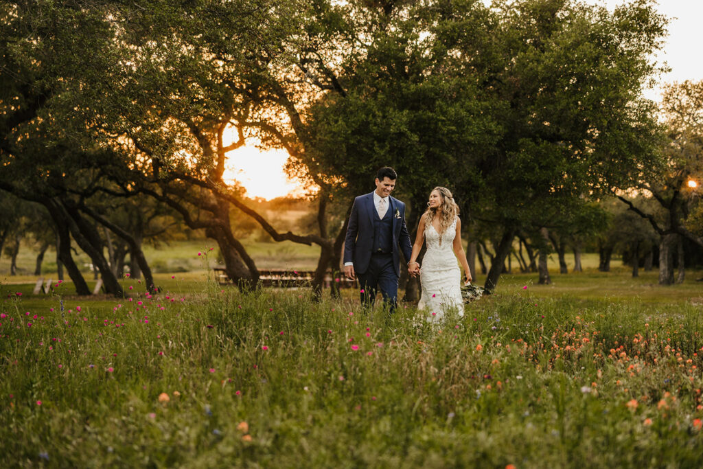 The couple strolls through a meadow at sunset