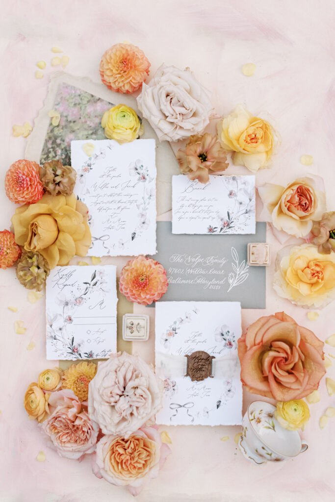 Flat lay wedding invitations with peach and yellow roses
