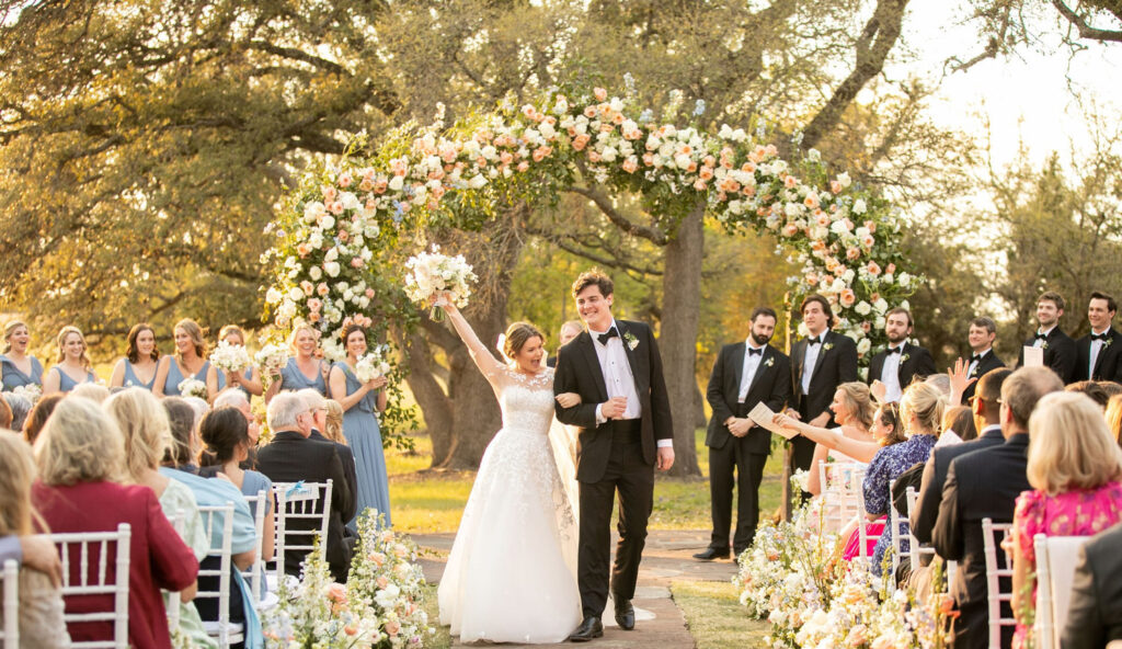 Couple walking down the aisle with guests cheering Taylor & Travis Inspired Engagement Party Ideas