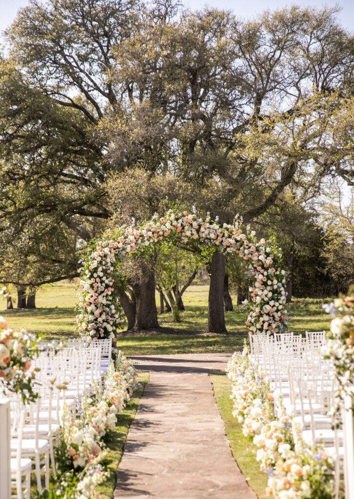 Outdoor ceremony aisle lined with flowers and arch