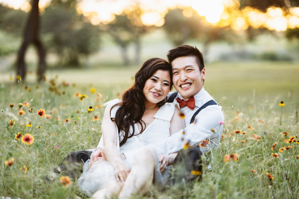 Married couple sitting in the field with naturally bloomed flowers