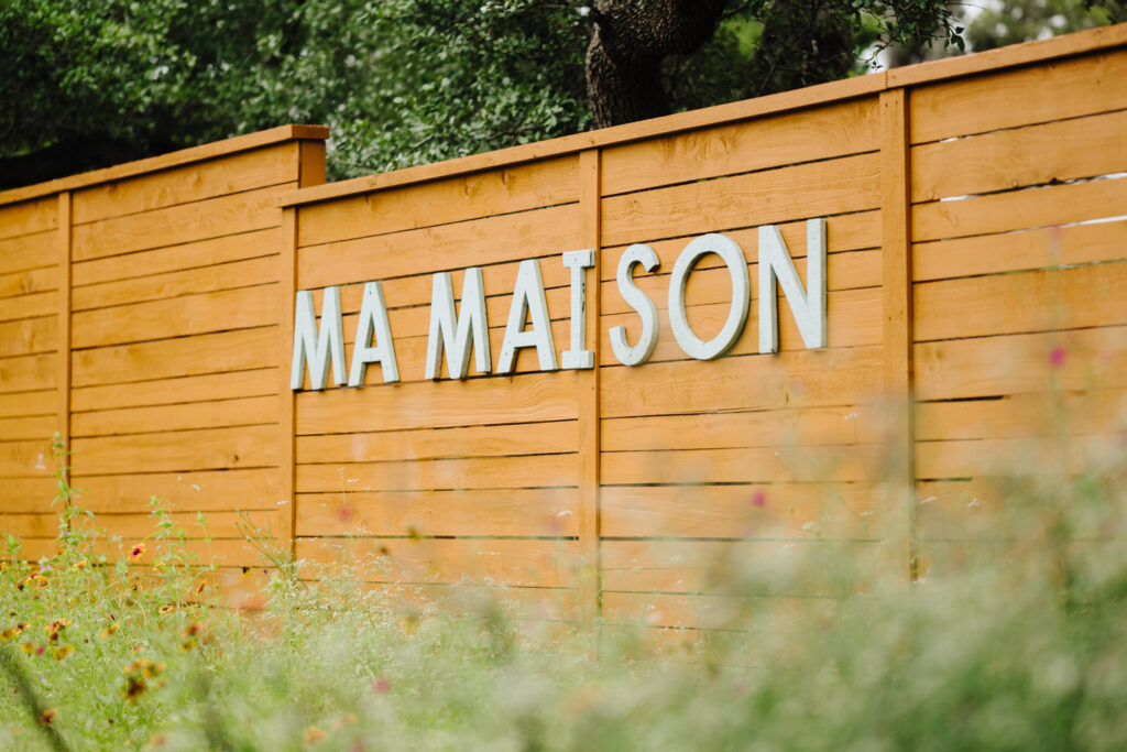 Ma Maison venue sign with floral backdrop in Texas Hill Country