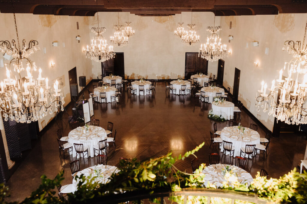Elegant reception setup with round tables and crystal chandeliers in a Tuscan-style ballroom