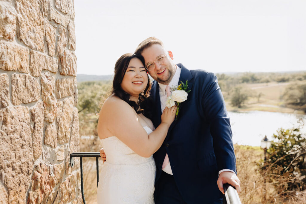 Close-up of newlyweds smiling with a lake and rolling hills in the background