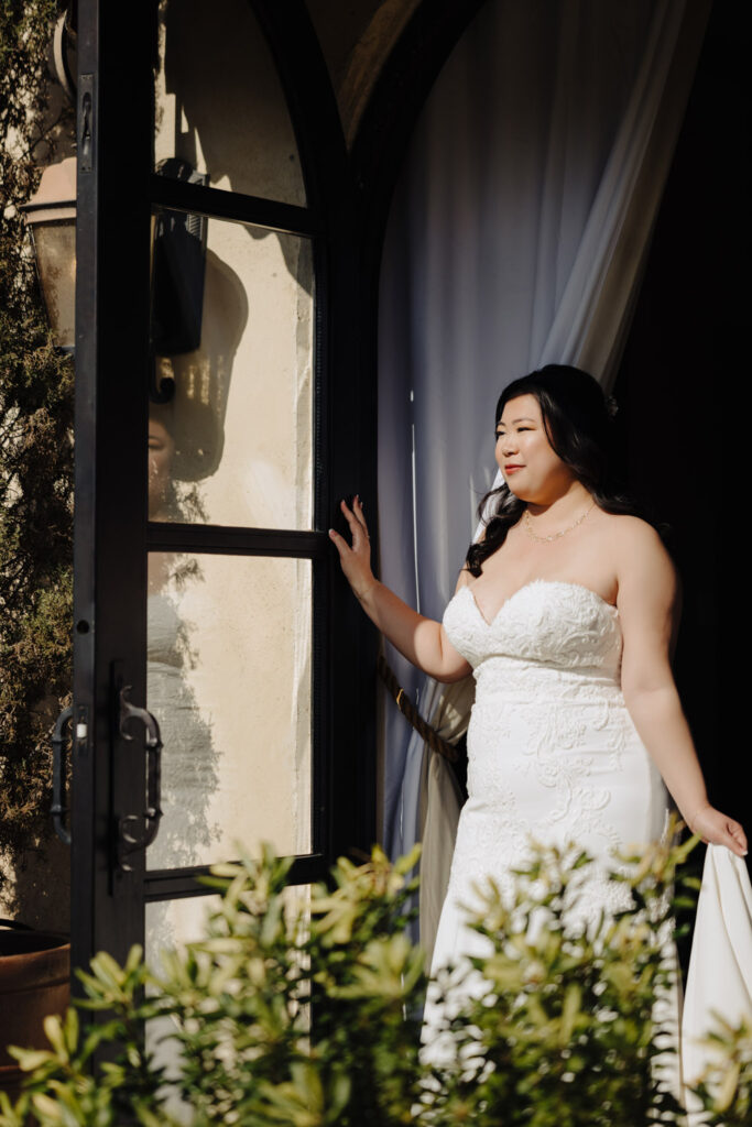 Bride steps through an arched doorway with sunlight and shadows