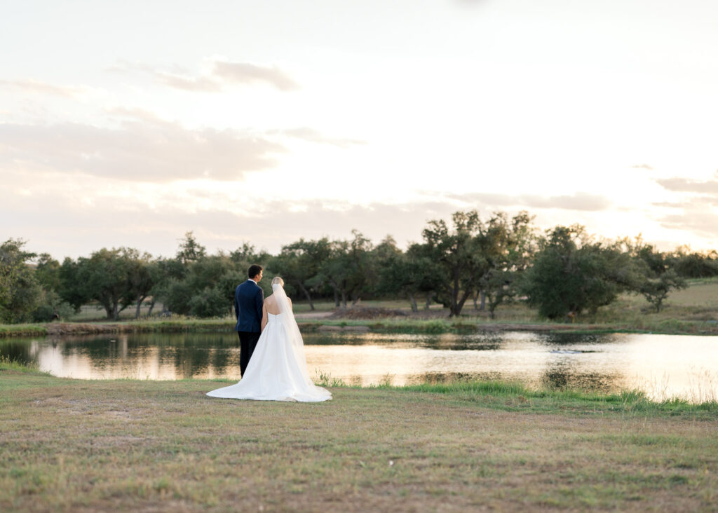 Bride and groom standing by the lake at sunset at a unique Austin wedding venue
