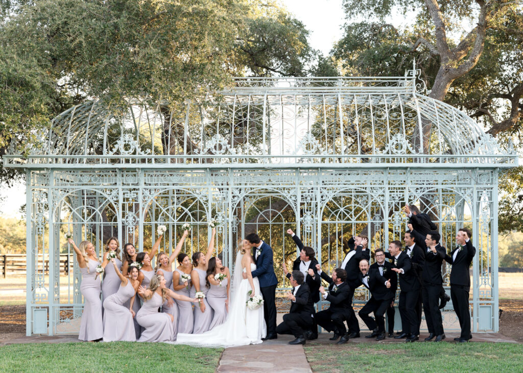 Wedding party celebrating around the couple in front of an iron pavilion at a unique Austin wedding venue