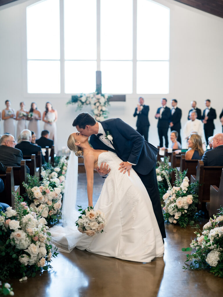 Bride and groom sharing a kiss during their ceremony in a chapel
