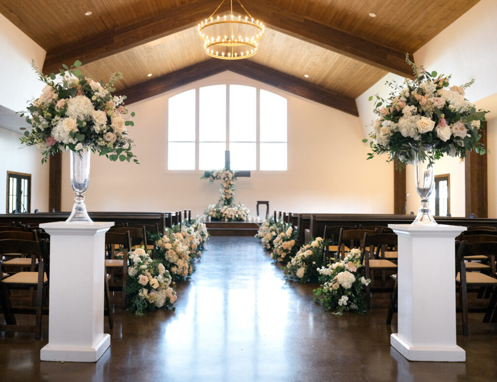 Floral-lined chapel aisle with tall arrangements at the entrance of a unique Austin wedding venue
