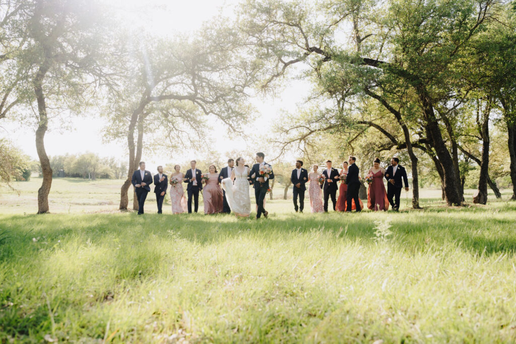 Wedding party walking through a sunlit field—fresh twist on formal portraits