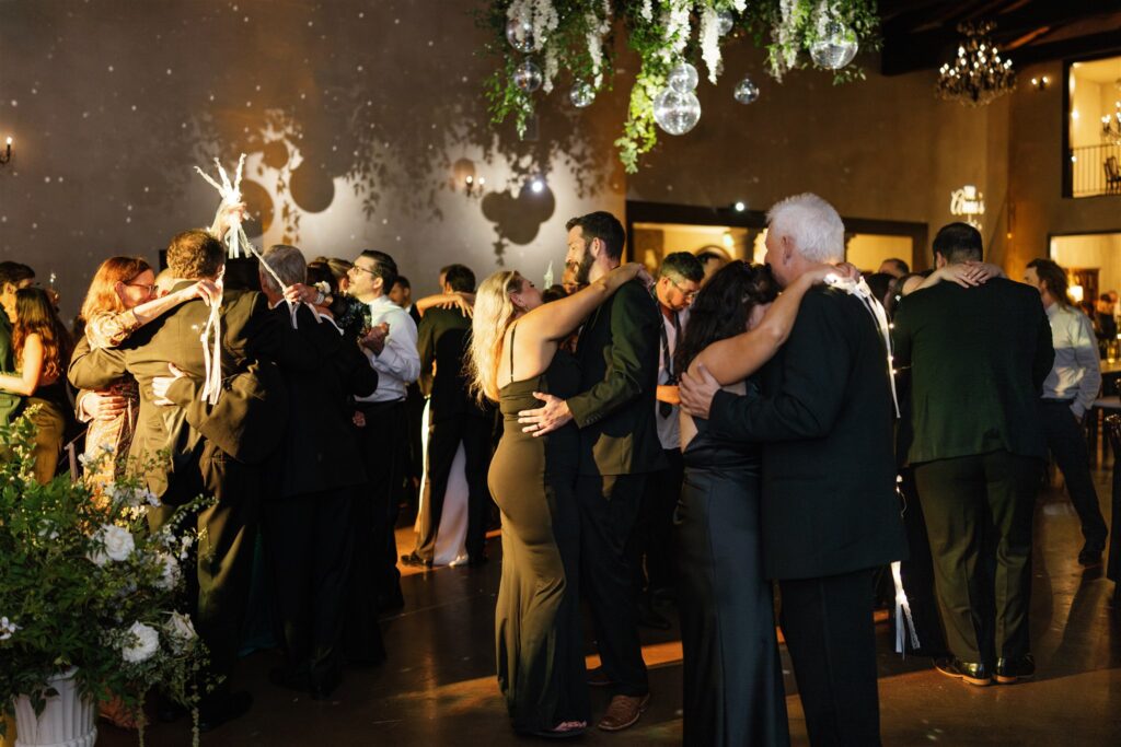 Guests slow dancing under disco lights at a wedding.
