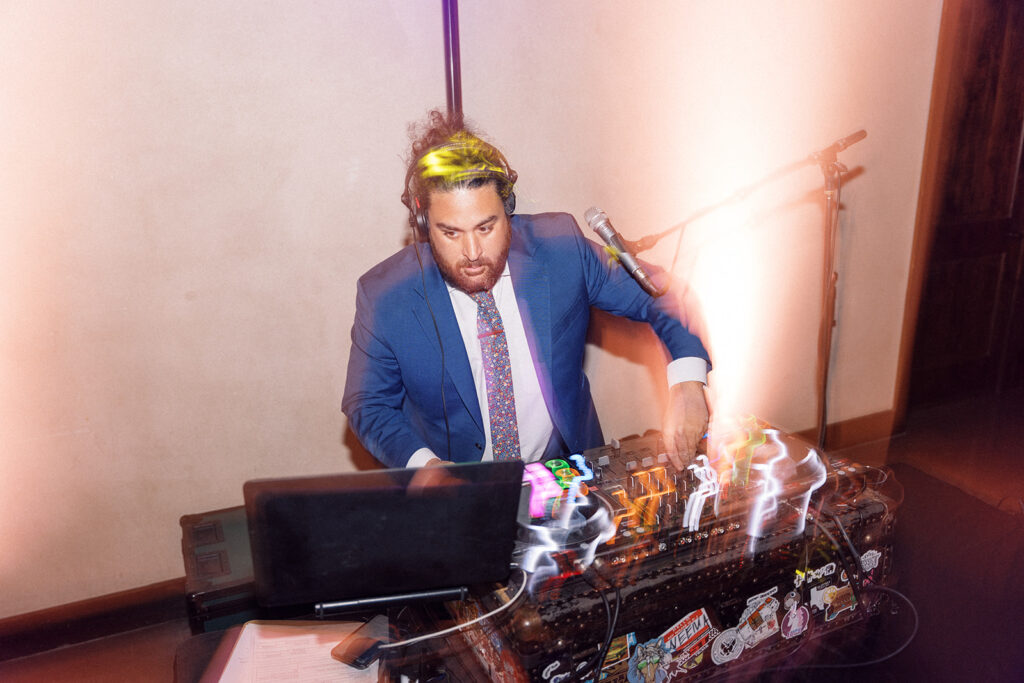 Wedding DJ in Austin spinning tracks in a blue suit.