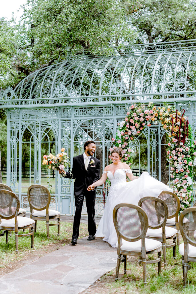 Couple walking through the floral ceremony setup at Ma Maison