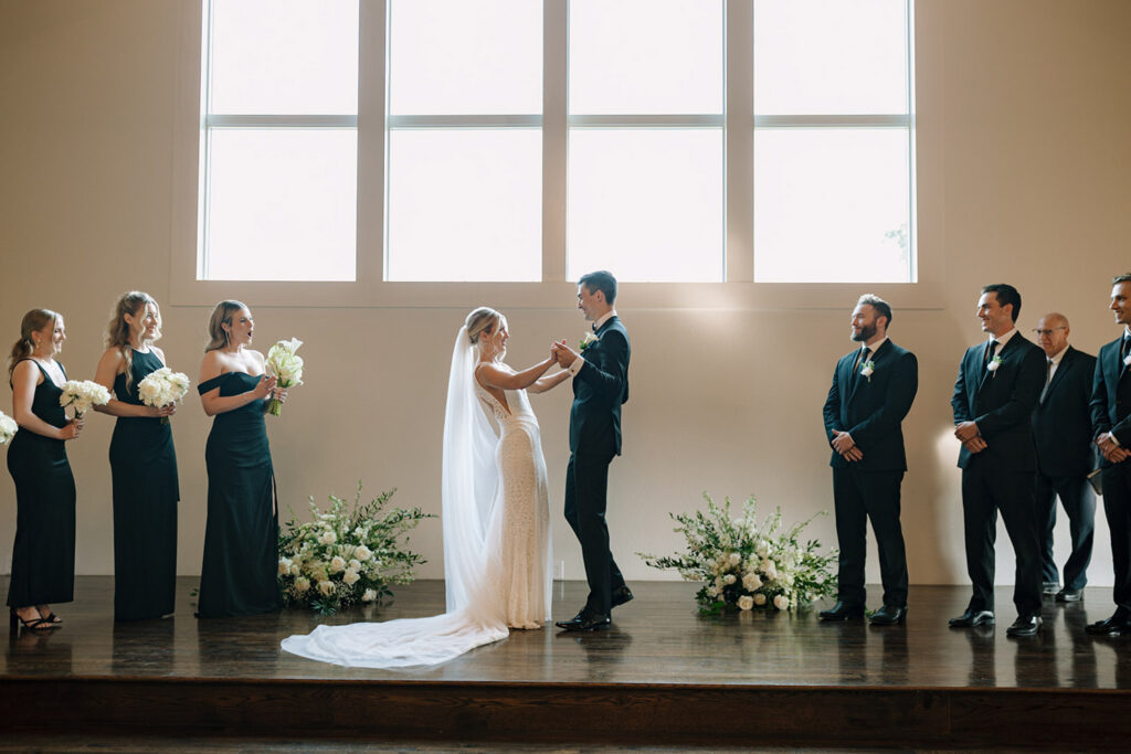 Bride and groom holding hands during their wedding ceremony.