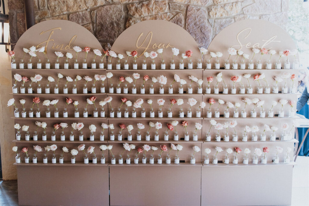 Wedding seating chart with an elegant rose and name on a small bottle