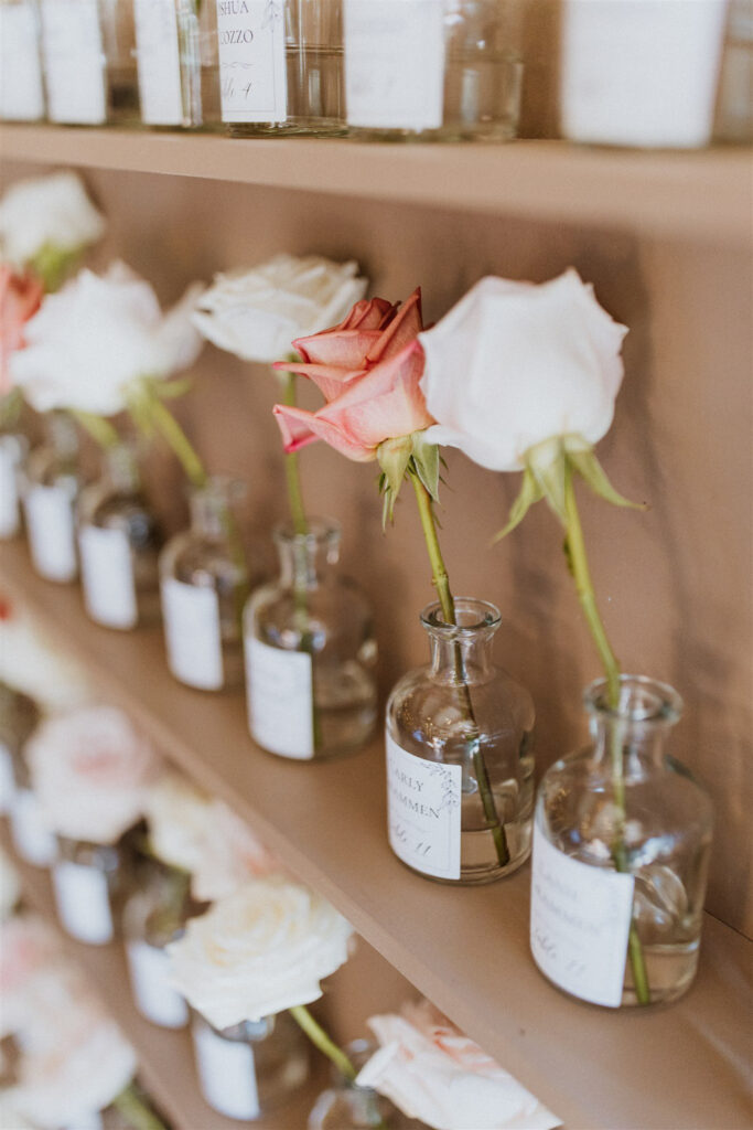 Wedding seating chart with a rose and name on the small bottle