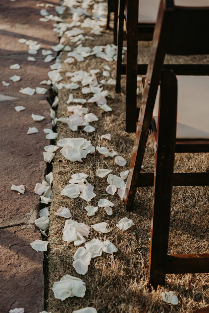 White rose petals scattered along aisle beside chairs