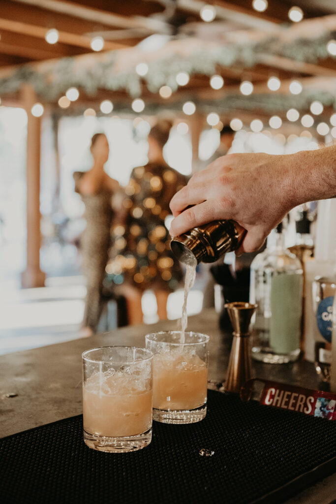 Bartender pouring cocktail into glasses at reception bar