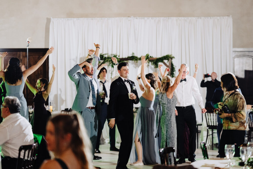 Married coupe alongside wedding guests dancing in the reception