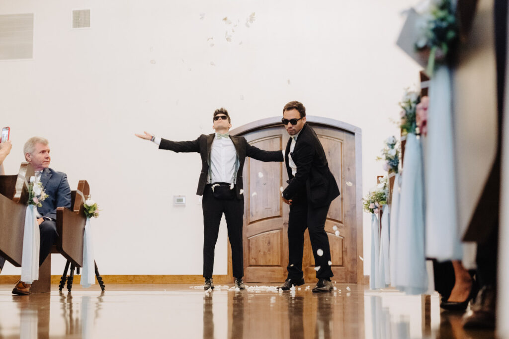 Two flower boys having fun throwing flowers in the aisle.