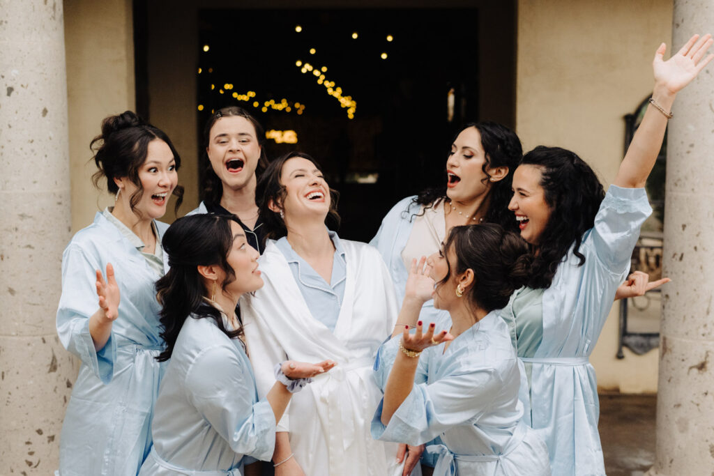 Bride and bridesmaids having fun outside wedding venue