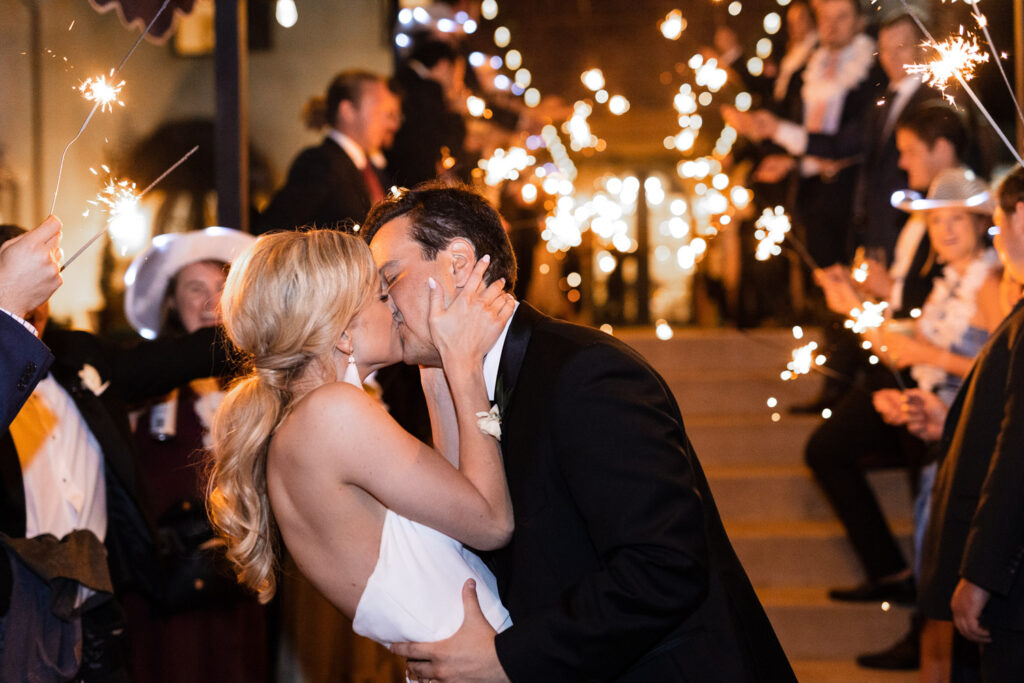 Bride and groom kissing during sparkler exit