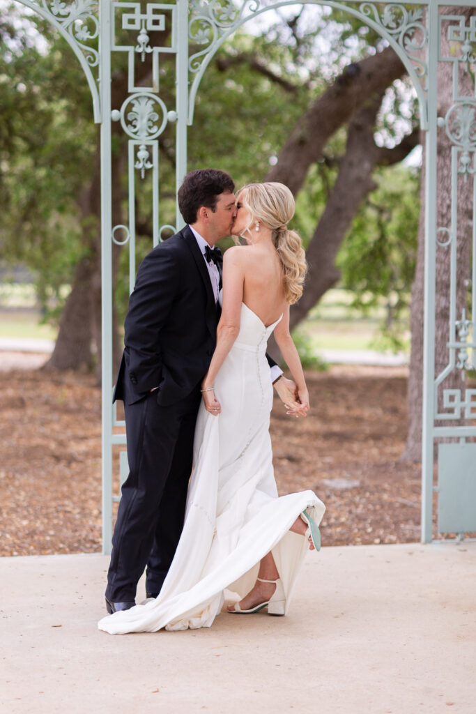 Bride and groom kissing under garden arch