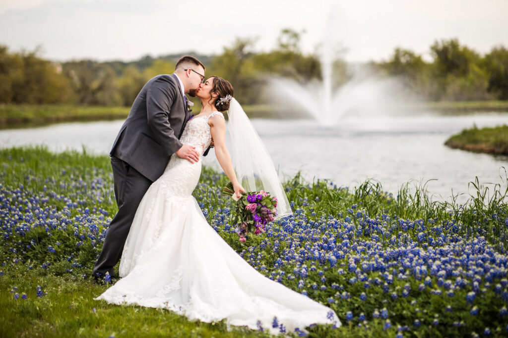 Bride and groom kissing in a field of Texas bluebonnets at Ma Maison