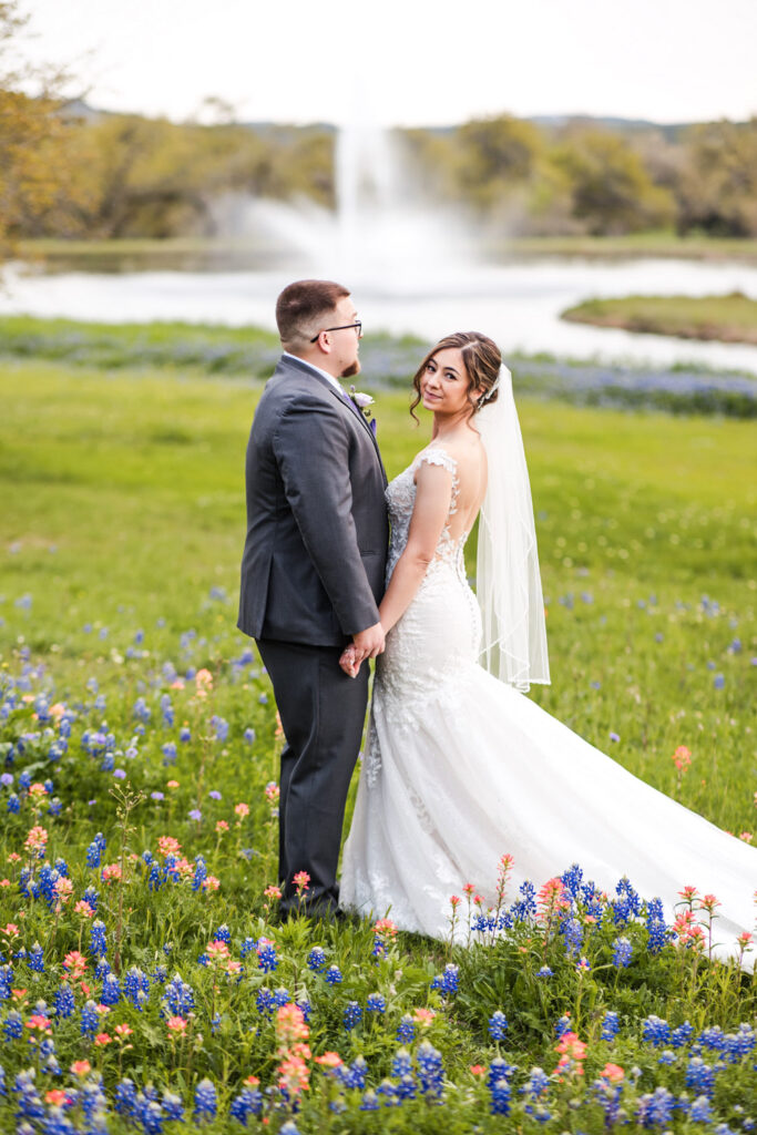 Bride and groom posing in front of the Ma Maison fountain and bluebonnets as an example of seasonal charm at Year-Round Austin Wedding Venues