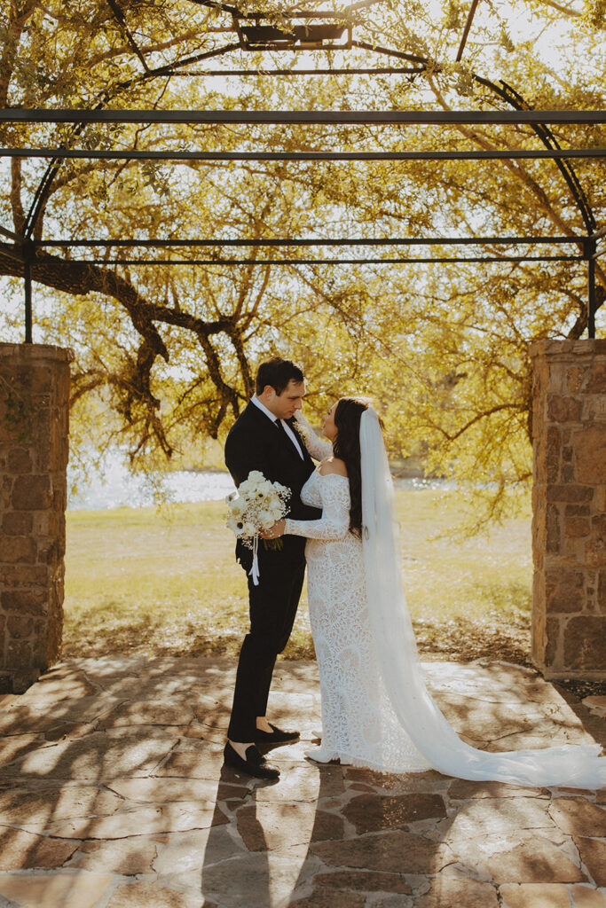 Couple standing beneath golden light in Ma Maison’s stone archway