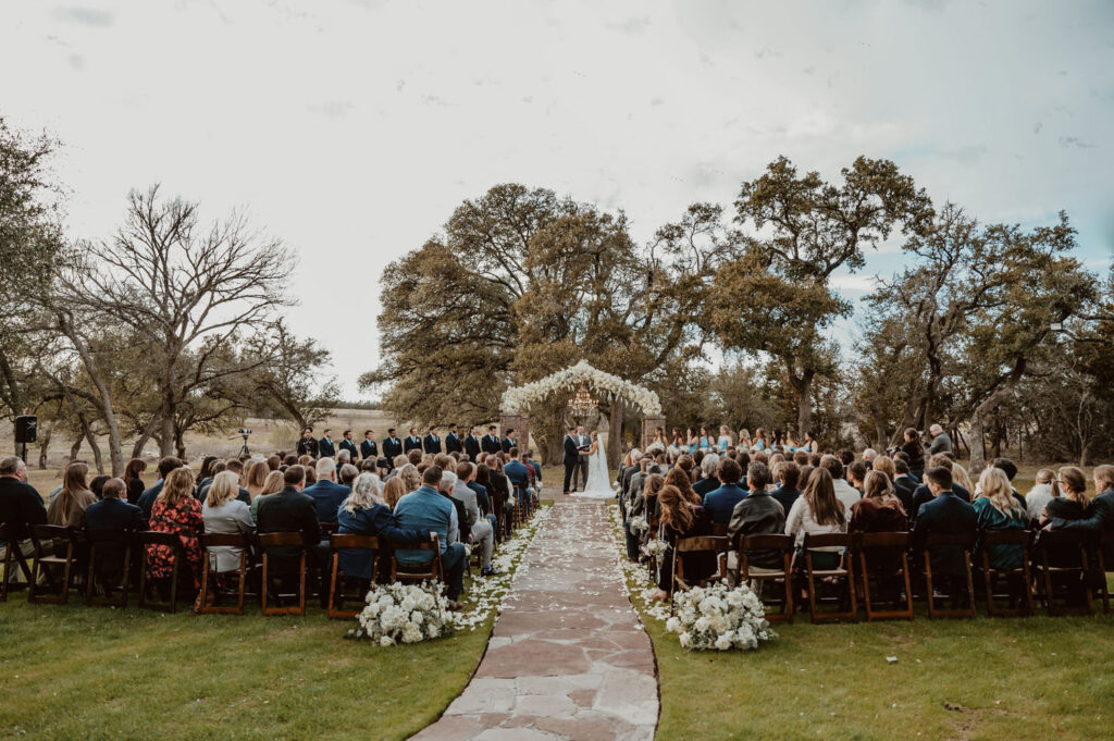 A breathtaking outdoor wedding ceremony at Ma Maison’s Green Cathedral, where a couple exchanges vows beneath a floral-adorned arch