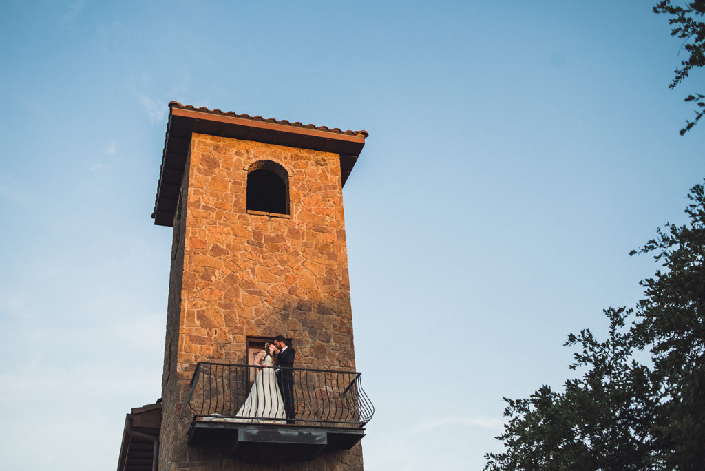 bride and groom kisses on balcony at outdoor Texas wedding venue