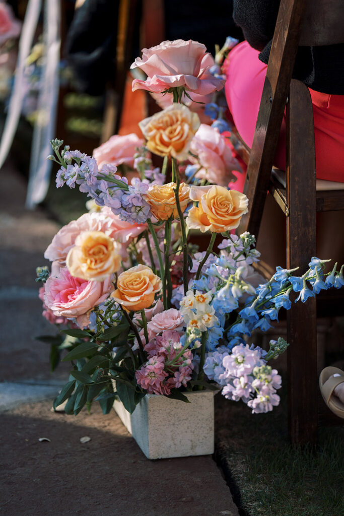 A ceremony aisle lined with peach roses and sky-blue delphiniums demonstrating flowers for wedding aisle décor