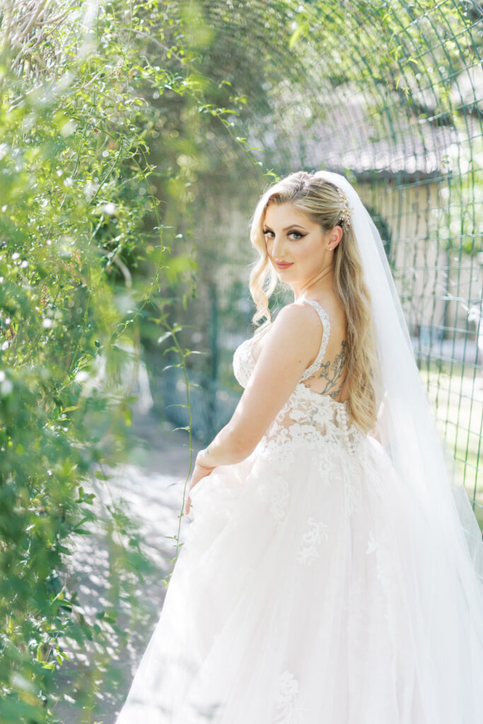 Bride in lace gown walking through tunnel of love