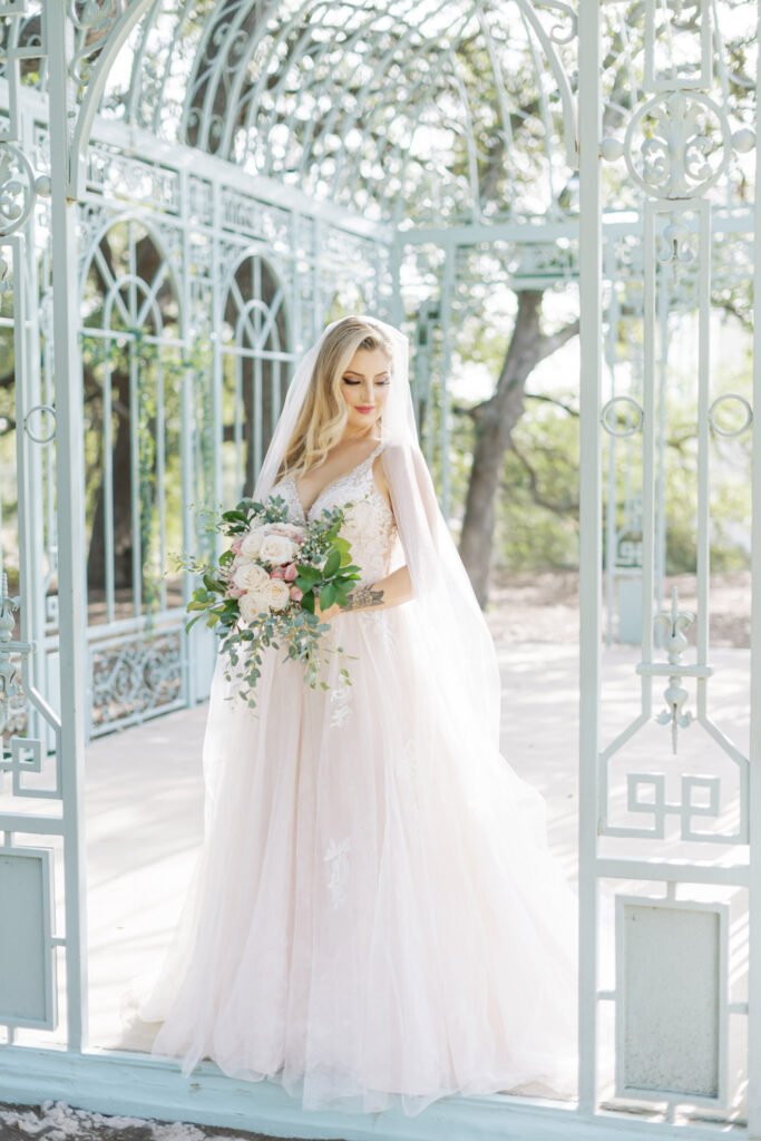 Bride holding bouquet inside iron gazebo