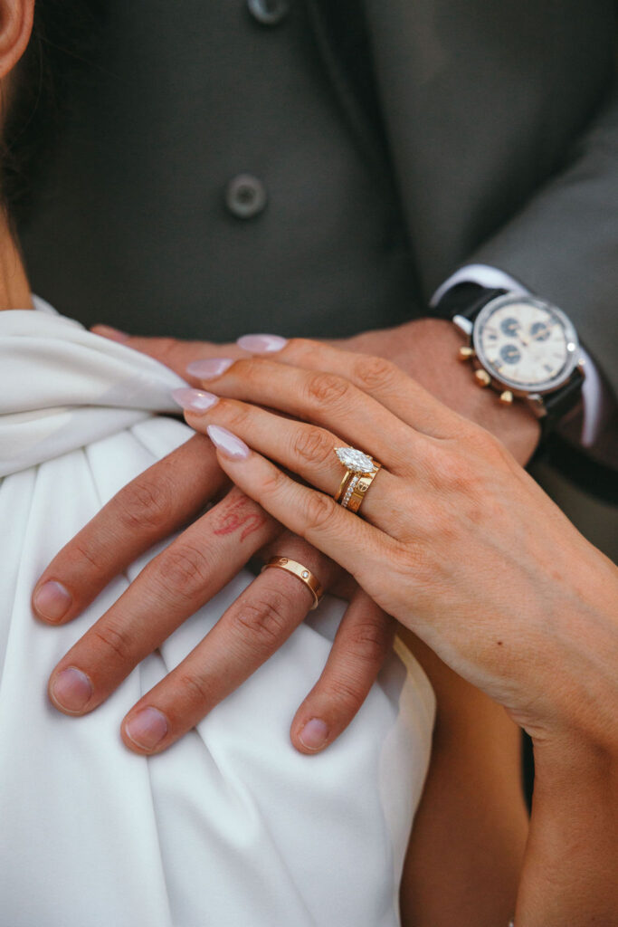 Detailed hands shot of couple showing lab-grown diamond and wedding bands
