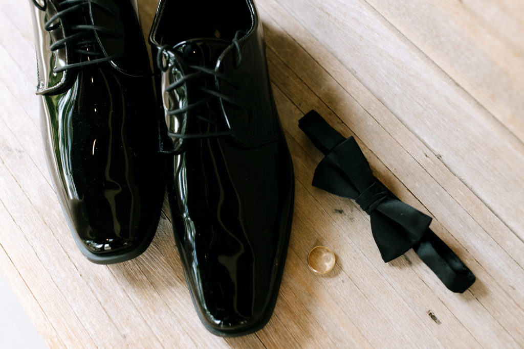 wedding details to consider on your special day - photo of groom's shoes, bowtie, and wedding band