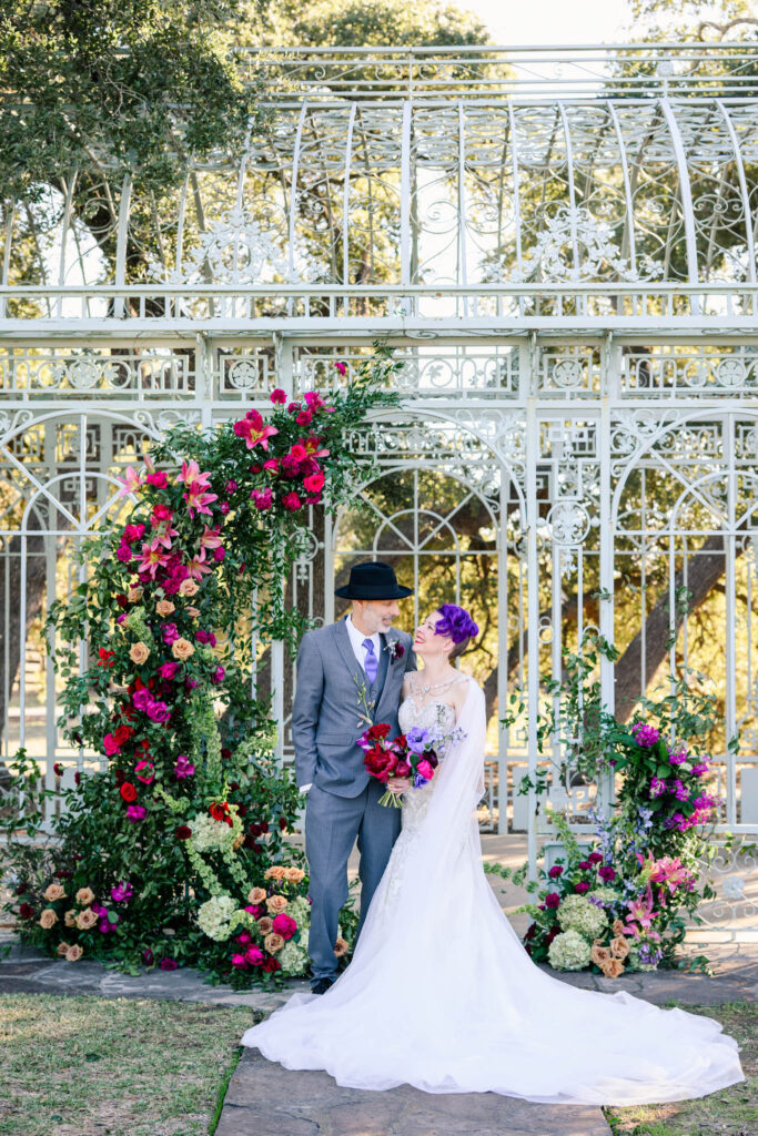 Bride and groom share a romantic moment in at Ma Maison's Green Cathedral, adorned with vibrant floral arrangements.