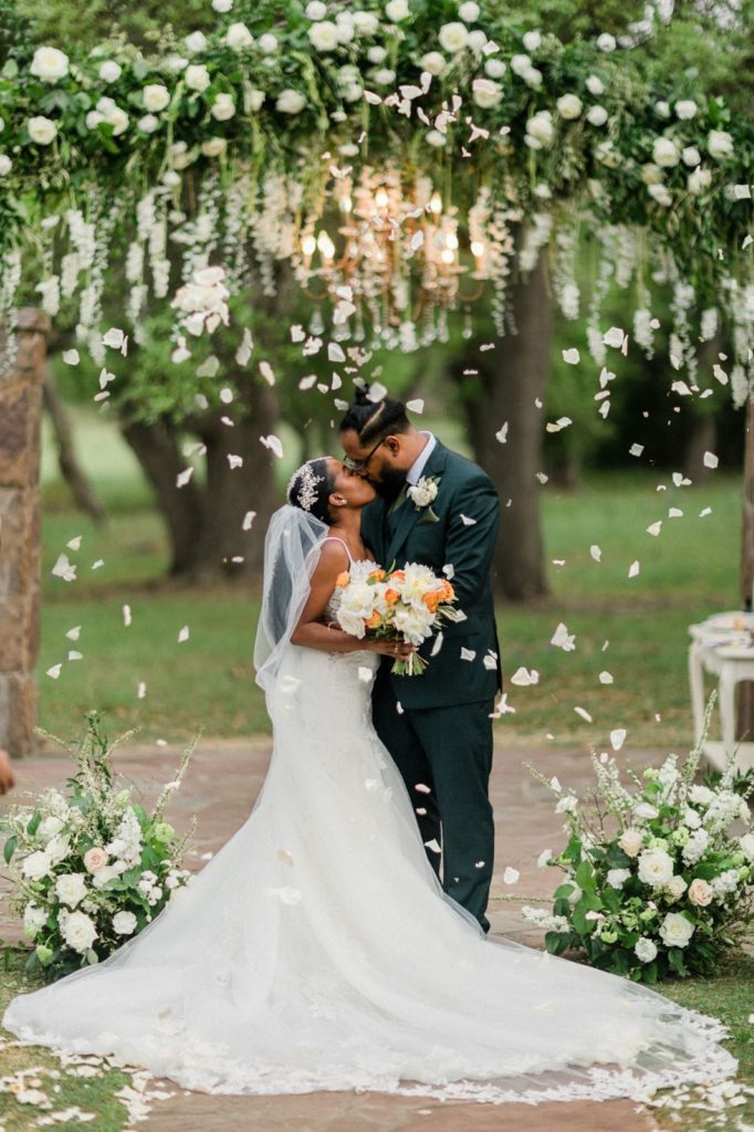 couple kissing under flowers outside at their Austin wedding