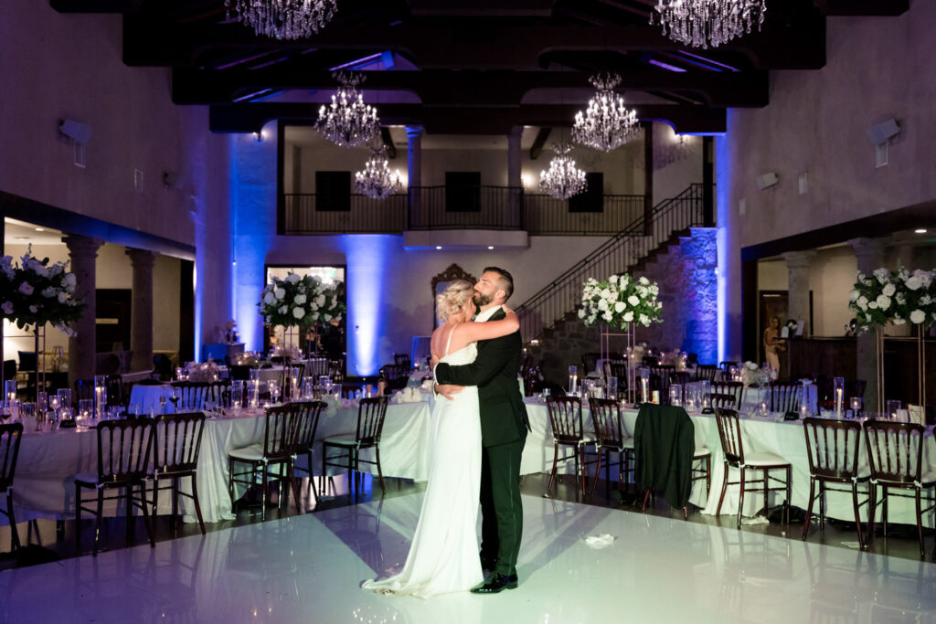 Couple sharing a romantic embrace on a glowing dance floor in Dripping Springs venue