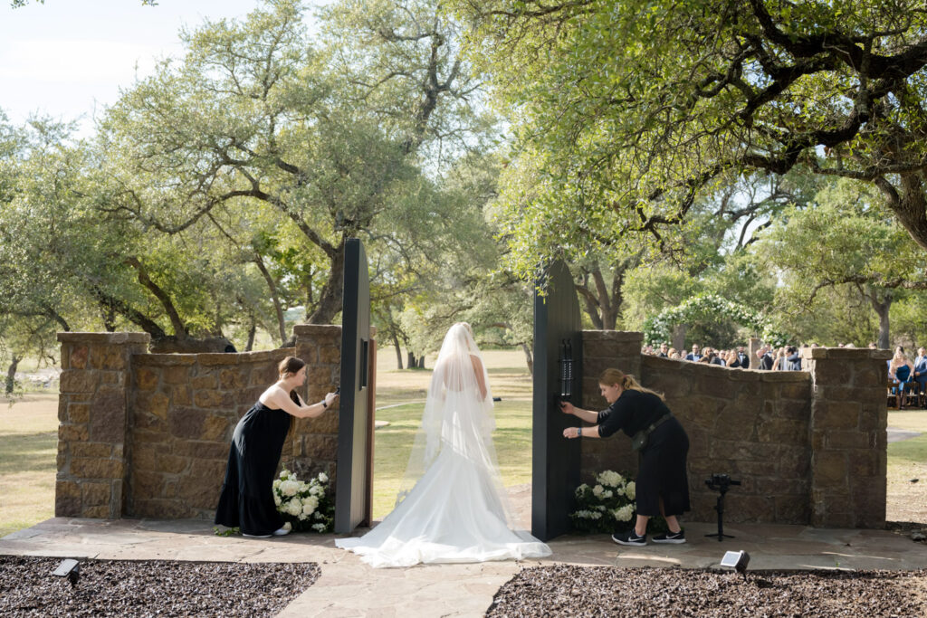 Bride entering ceremony through dramatic black doors at romantic Dripping Springs location