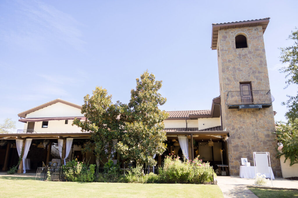 Sunny view of romantic stone venue in Dripping Springs with tower and draped patio